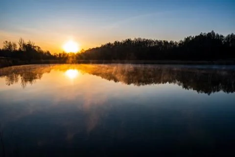 Sunrise over the lake with tree reflection and beautiful fog Stock Photos