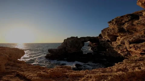 Sunrise over naturally made arc in the cliffs of Black Sea Stock Footage 148514381