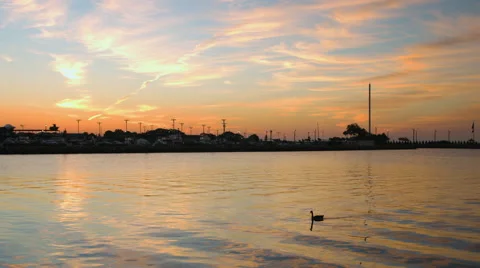 Sunrise over the ocean casting orange and blue sky and clouds during the summer Stock Footage 64900938