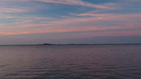 Sunrise over the ocean casting orange and blue sky and clouds during the summer Stock-Footage 64901095