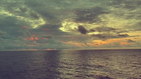 Sunrise over the ocean with clouds reflecting warm light on the water surface Stock Footage 338281467