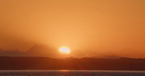 Sunrise over ocean  with mountains in background while sea birds fly by Stock Footage 220923761