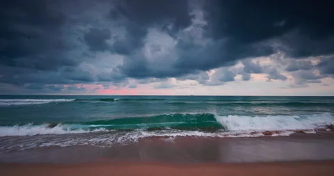 Sunrise over ocean waves and sandy beach with dark dramatic sky Stock Footage 317546281