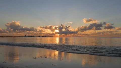 Sunrise over the ocean while waves lap on the beach Video stock 272661309