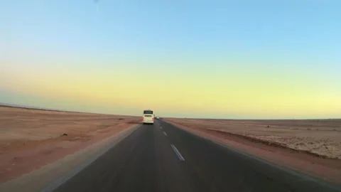 Sunrise over road in Egypt in the middle of the desert with a tourists bus dr Stock Footage 203304599