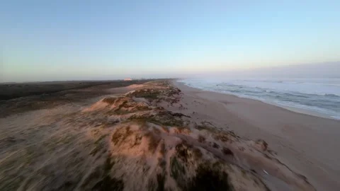 Sunrise over sandy coastal dunes with ocean waves Video stock 346074535