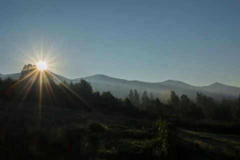 Sunrise over the top of the mountain. Rays flooding a misty valley Stock Photos