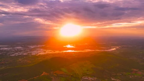 Sunrise over valley with clouds and glowing sun above mountains and reflections Stock Footage 320455494