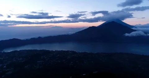 Sunrise over volcano with clouds on top and lake at the bottom Video stock 114584537