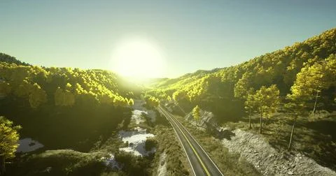 Sunrise over winding road through vibrant autumn forest in mountainous region Ilustração Stock