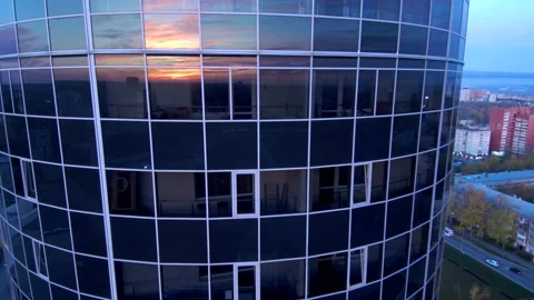 Sunrise is reflected in the glass wall of a skyscraper in a modern city. Stock Footage 132579740