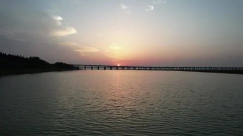 Sunrise Reflected On Lake Beside Long Bridge in Shijiu Lake, China Stock Footage 344039730