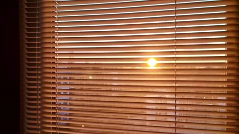 Sunrise shining through window blinds creating warm, peaceful morning atmosphere Stock Footage 315622825