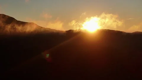 Sunrise sun burst behind dramatic cloud over mountain silhouette Stock-Footage 336816426