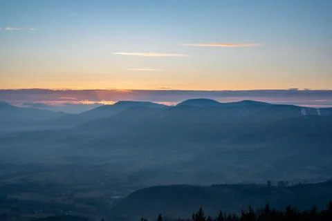Sunrise sun hidden behind cloud in mountains with fog in valley Stock Photos