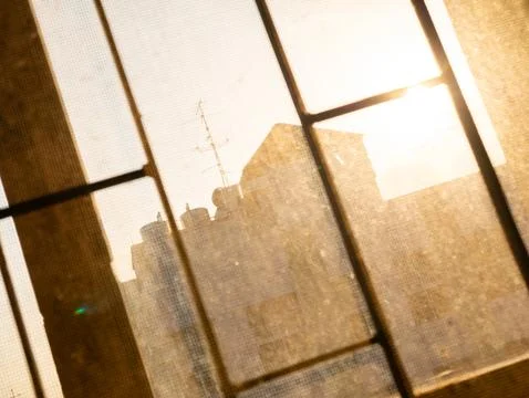 Sunrise Through Dusty Window Screen with Rooftop Silhouette, Urban Morning .. Stock Photos