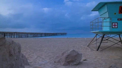 Sunrise time lapse on beach with pier and lifeguard tower Stock Footage