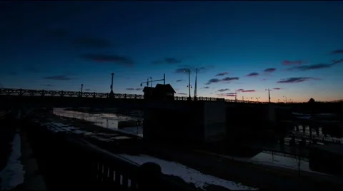 Sunrise time-lapse cloudscape with bridge and ice moving down river Stock Footage 7746847