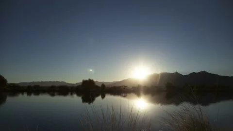 Sunrise time lapse over a reflecting lake on a clear day Stock Footage 164790693