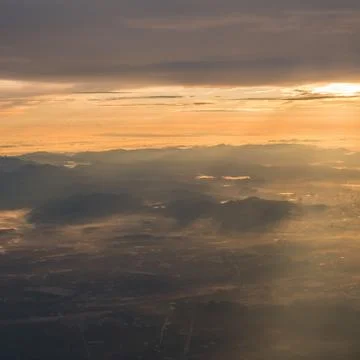 Sunrise view above the clouds with dramatic light from airplace window Stock Photos