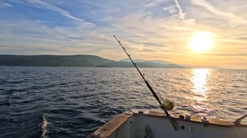 A sunrise view over calm waters with a fishing rod positioned on the boat. Stock Footage 289851834