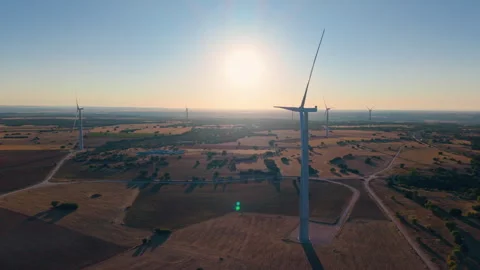Sunrise view of wind turbines with long shadows across rural countryside Video stock 317639722
