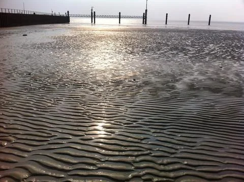 The suns light is mirrored on the waters surface at the beach Emden Germany Stock Photos