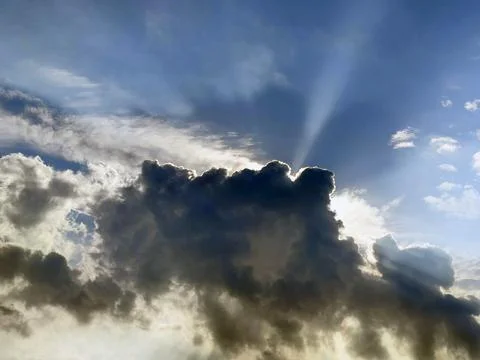 The sun's rays breaking through behind a thundercloud. Dramatic sky backgroun Stock Photos
