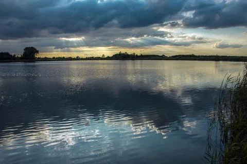 The sun's rays in the clouds over a calm lake Stock Photos
