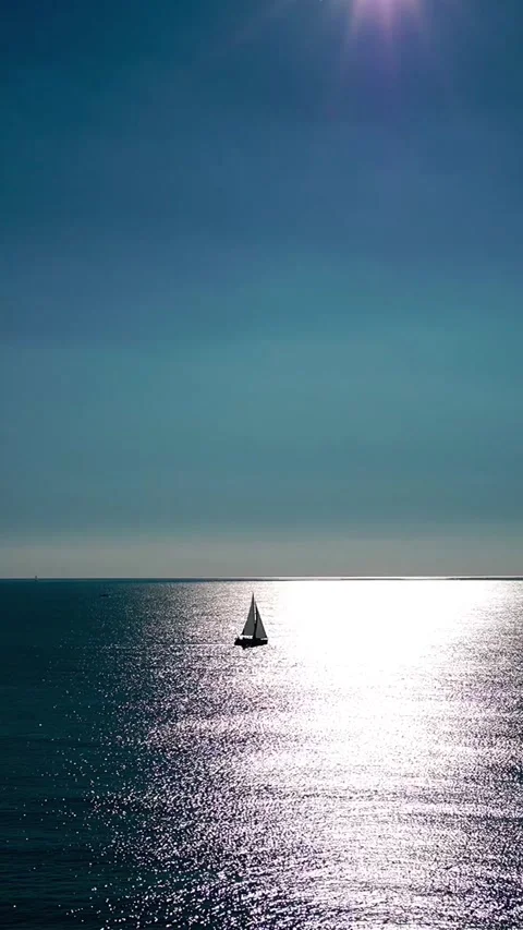 The sun's rays glisten on the water's surface, revealing the horizon and a yacht Stock Footage 327081238