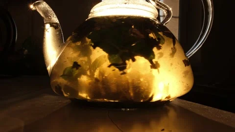 The sun's rays illuminate the transparent teapot. The process of brewing tea Stock Footage 172220237