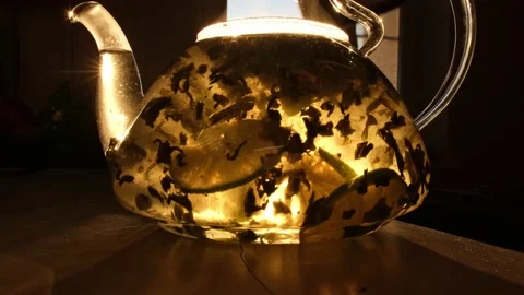 The sun's rays illuminate the transparent teapot. The process of brewing tea Stock Footage 172266865