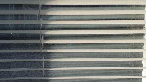 The sun's rays make their way through the blinds in the evening at sunset. Video stock 143341321