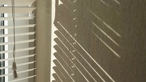The sun's rays make their way through the blinds in the evening at sunset. Stock Footage 143346754