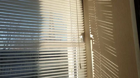 The sun's rays make their way through the blinds in the evening at sunset. Video stock 143346819