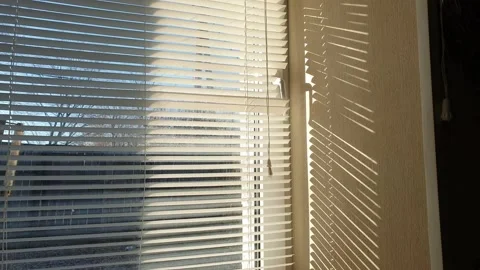 The sun's rays make their way through the blinds in the evening at sunset. Vídeo Stock 143346890