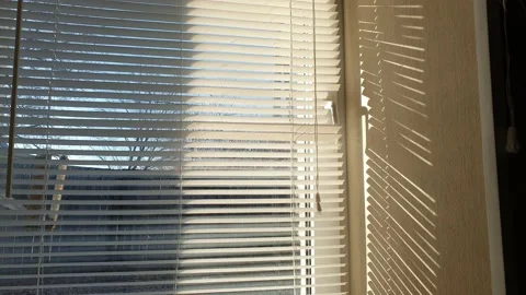 The sun's rays make their way through the blinds in the evening at sunset. Video stock 143346899