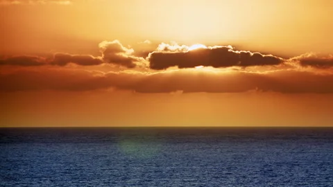 The Sun's rays make their way through the Golden clouds above the Water. Stock Footage 151548381