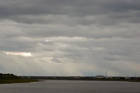 The sun's rays make their way through the clouds illuminating the village of Stock Photos