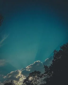 The sun's rays make their way through the clouds. Evening photo. Graininess of Stock Photos