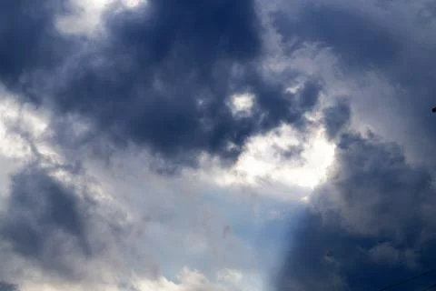 The sun's rays make their way through the dark stormy sky Stock Photos