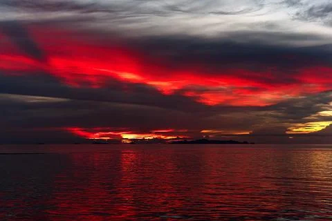 The sun's rays painted the clouds and the sea with scarlet colors Foto stock