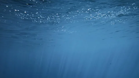 The sun's rays pass through the blue clear water of the ocean. Shot under water Stock Footage 107046278