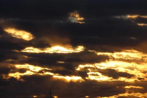 The suns rays pass through the dark clouds. Beautiful dramatic sky at sunset or Stock Photos