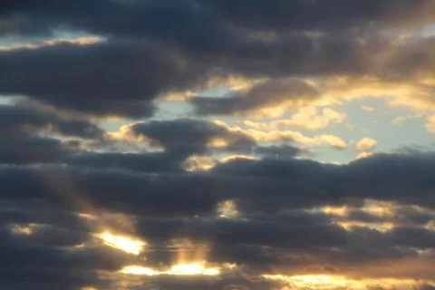 The suns rays pass through the dark clouds. Beautiful dramatic sky at sunset or Stock Photos