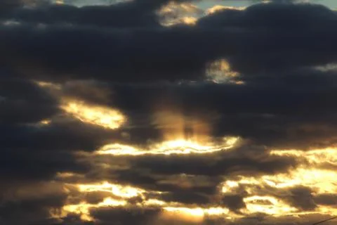 The suns rays pass through the dark clouds. Beautiful dramatic sky at sunset or Stock Photos
