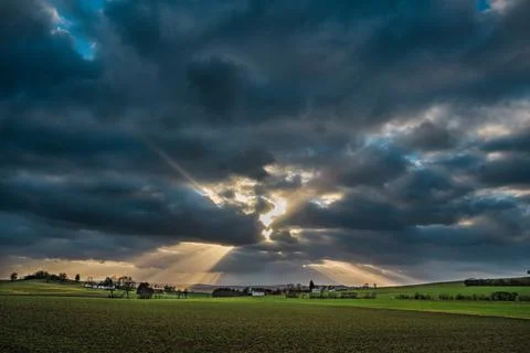 The sun's rays pierce the clouds over the agricultural field Stock Photos