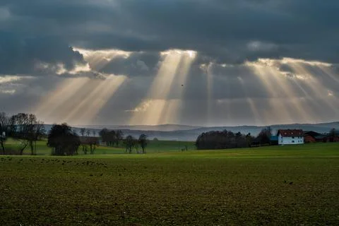 The sun's rays pierce the clouds over the agricultural field Stock Photos