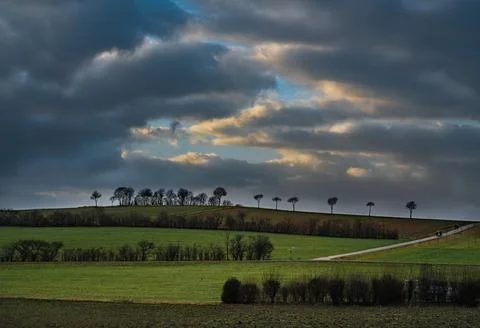 The sun's rays pierce the clouds over the agricultural field Stock Photos
