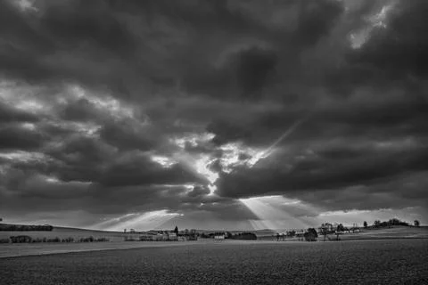 The sun's rays pierce the clouds over the agricultural field Foto stock